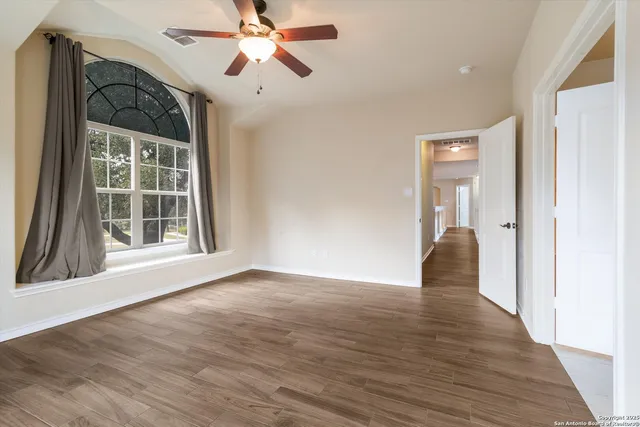 a view of an empty room with wooden floor and a window