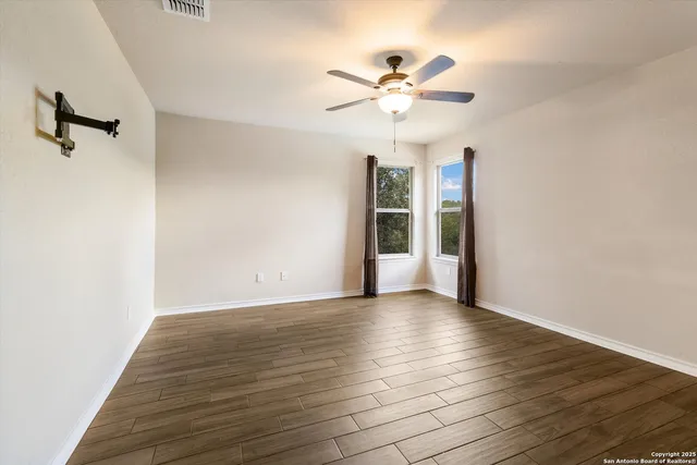 a view of an empty room with a window and wooden floor