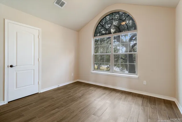 an empty room with wooden floor cabinet and windows
