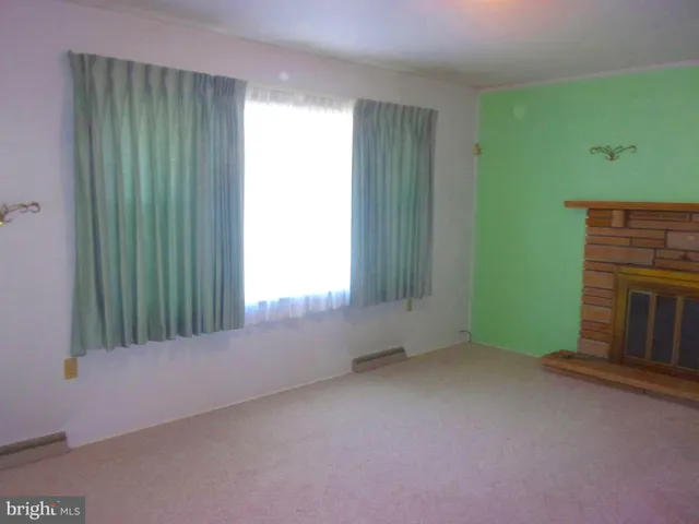 an empty room with windows and fireplace