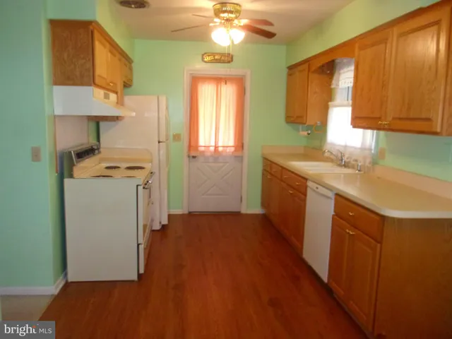 a kitchen with a sink a stove cabinets and wooden floor