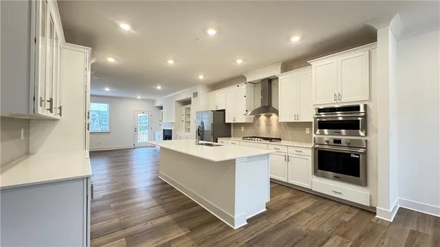 a kitchen with stainless steel appliances kitchen island granite countertop a stove and a sink