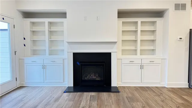 an empty room with wooden floor fireplace and windows