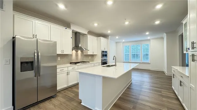 a kitchen with stainless steel appliances granite countertop a refrigerator a sink dishwasher a stove and a refrigerator with wooden floor