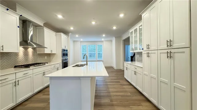 a large kitchen with stainless steel appliances granite countertop a stove a sink and white cabinets