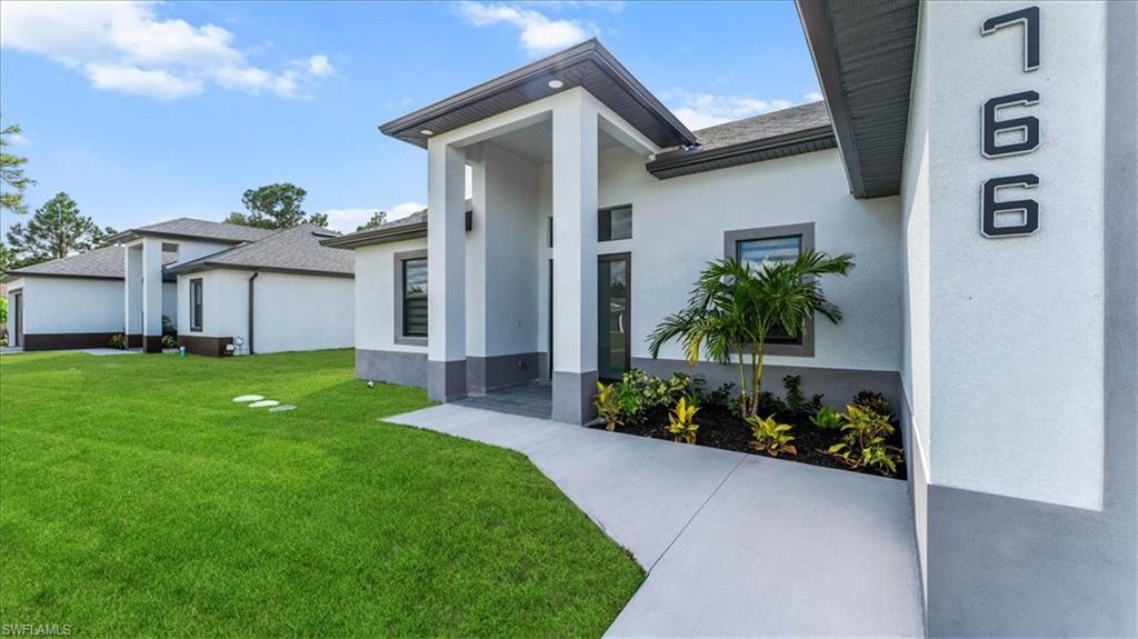 766 Roma Avenue South Lehigh Acres, FL 33974 - Photo 2 of 50 a front view of a house with a garden