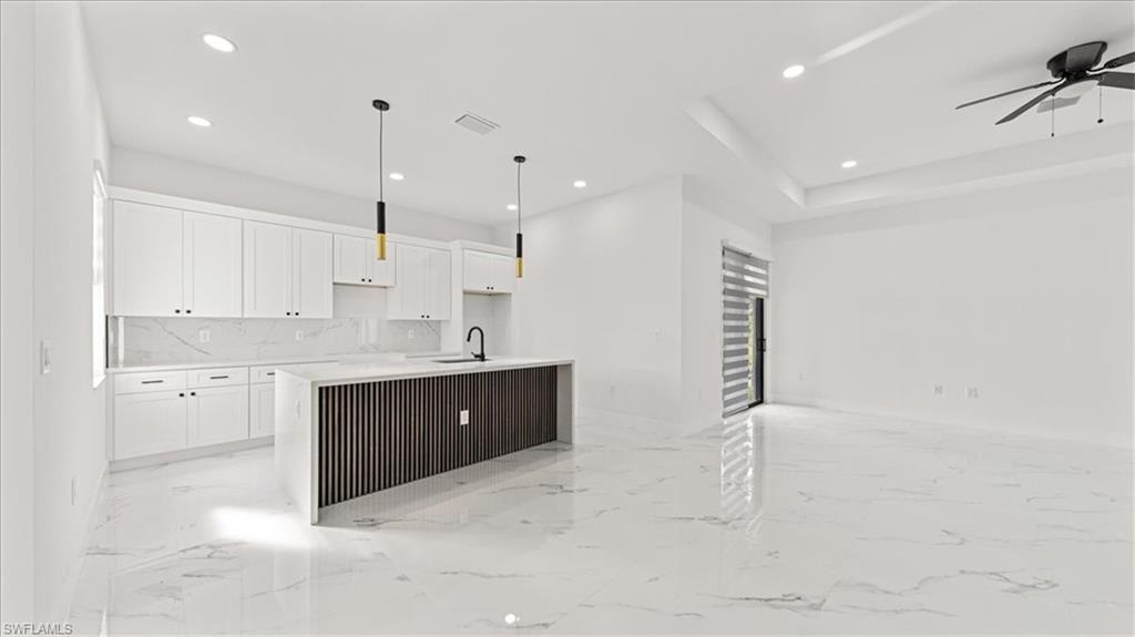 766 Roma Avenue South Lehigh Acres, FL 33974 - Photo 10 of 50 a large kitchen with kitchen island a sink stainless steel appliances and cabinets