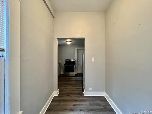 a view of an empty room with wooden floor