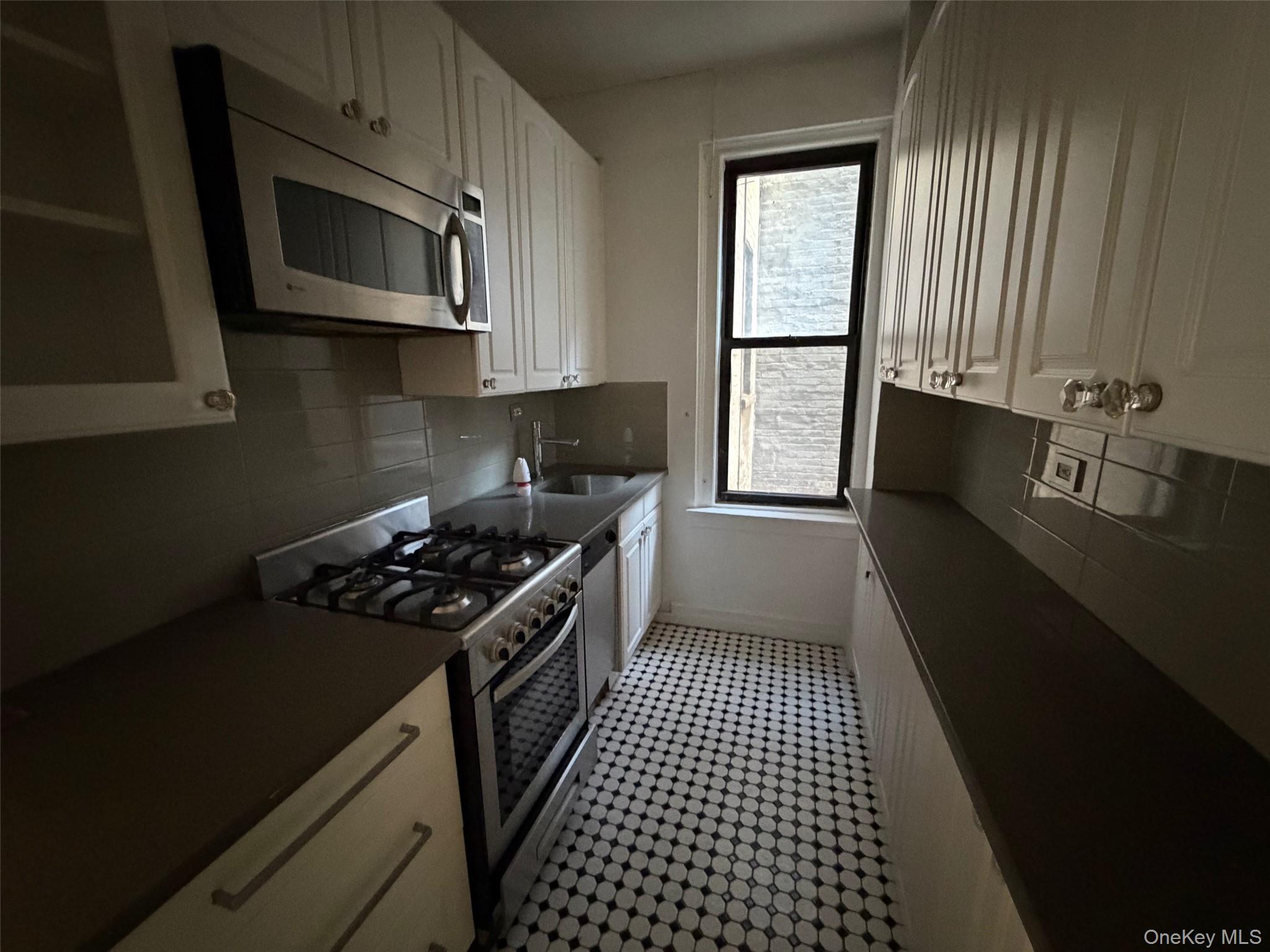 142 East 49th Street, Unit 8A Manhattan, NY 10017 - Photo 11 of 12 a kitchen with a stove a microwave and window
