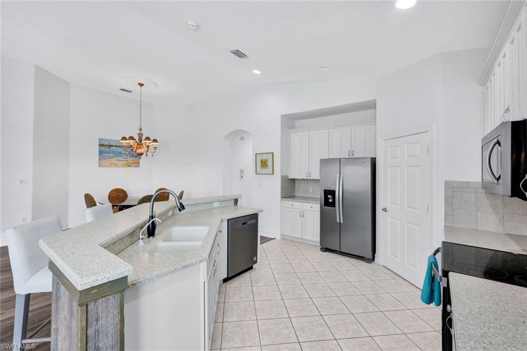 1277 Rialto Way, Unit 201 Naples, FL 34114 - Photo 11 of 46 a kitchen with a sink refrigerator and microwave
