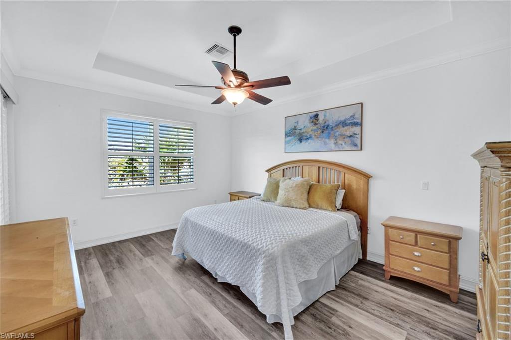 1277 Rialto Way, Unit 201 Naples, FL 34114 - Photo 14 of 46 a bedroom with a bed a window and a chandelier