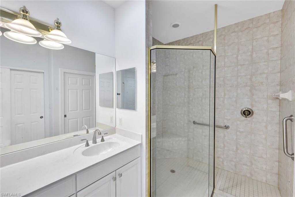 1277 Rialto Way, Unit 201 Naples, FL 34114 - Photo 17 of 46 a bathroom with a shower sink vanity granite and mirror