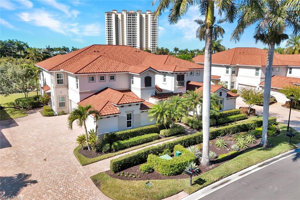 1277 Rialto Way, Unit 201 Naples, FL 34114 - Photo 23 of 46 a view of a white house with a yard and potted plants