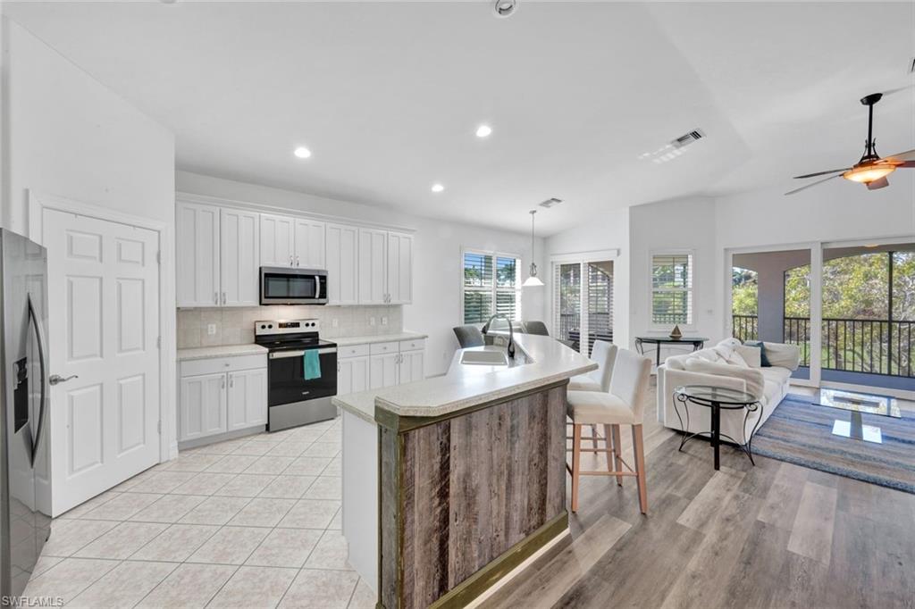 1277 Rialto Way, Unit 201 Naples, FL 34114 - Photo 8 of 46 a kitchen with kitchen island granite countertop a sink appliances and cabinets