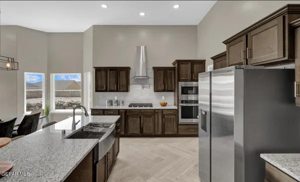 a kitchen with stainless steel appliances granite countertop a refrigerator a stove and a sink