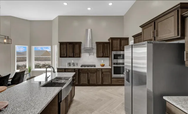 a kitchen with stainless steel appliances granite countertop a refrigerator a stove and a sink