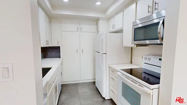 a kitchen with white cabinets and stainless steel appliances