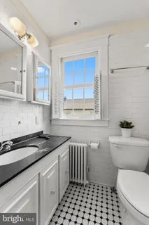 a bathroom with a granite countertop toilet a sink a window and a shower