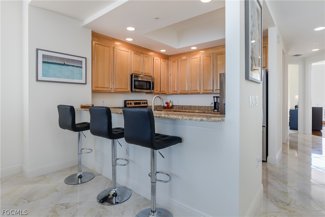 2090 West First Street, Unit J2510 Fort Myers, FL 33901 - Photo 8 of 50 a kitchen with stainless steel appliances kitchen island granite countertop a refrigerator a stove a sink and a dining table with wooden floor