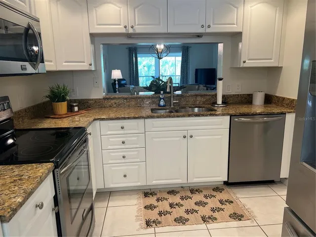 a kitchen with granite countertop a sink a stove and cabinets