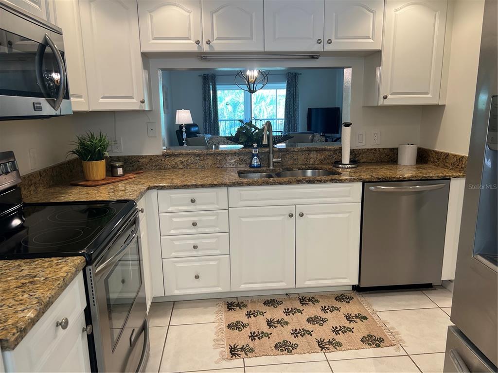6501 Stone River Road, Unit 309 Bradenton, FL 34203 - Photo 21 of 33 a kitchen with granite countertop a sink a stove and cabinets