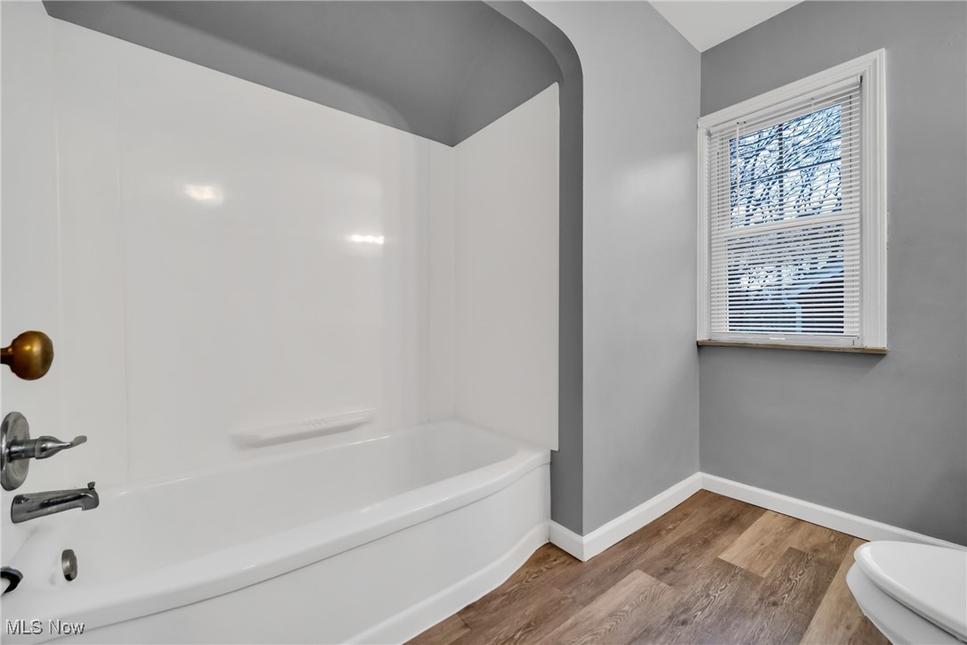 1605 Laclede Road Cleveland, OH 44121 - Photo 15 of 40 Bathroom featuring toilet, baseboards, bathtub / shower combination, and wood finished floors