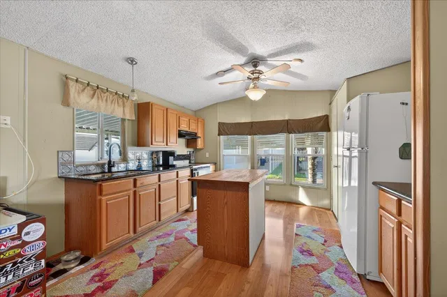 a kitchen with stainless steel appliances granite countertop a refrigerator a oven a sink and dishwasher with wooden floor