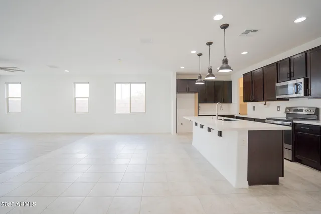 a large kitchen with stainless steel appliances kitchen island granite countertop a large stove a sink dishwasher and a refrigerator with wooden floor