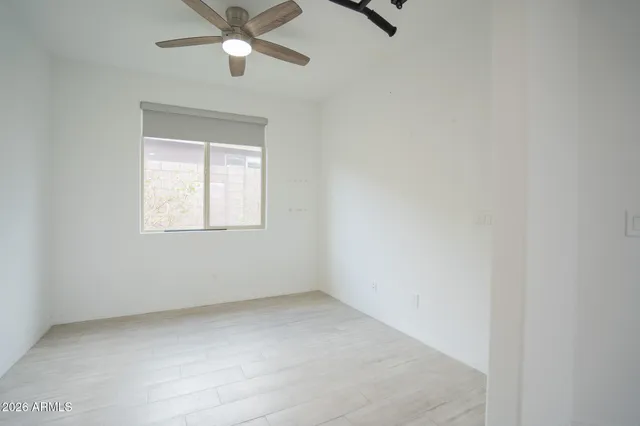 an empty room with a window and a fan