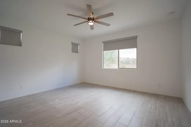 an empty room with a window and a ceiling fan