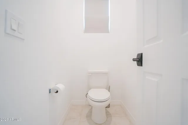 a white toilet sitting next to a white wall
