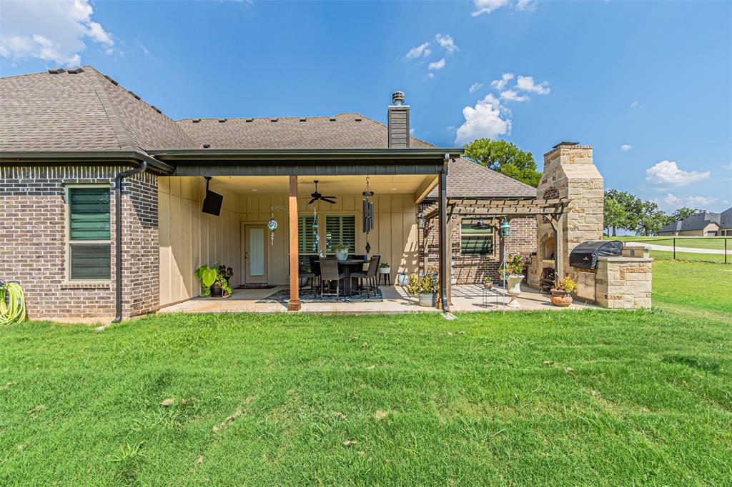 1009 Henry Way Springtown, TX 76082 - Photo 36 of 40 Back of property featuring a patio, ceiling fan, a yard, roof with shingles, and board and batten siding