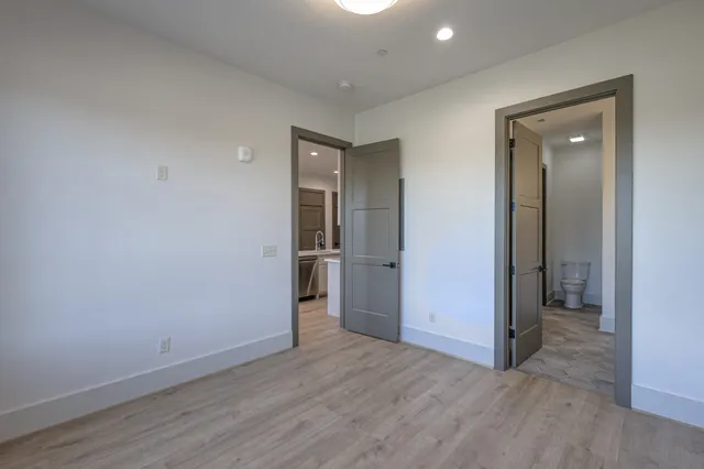 a view of a hallway with wooden floor and a bathroom
