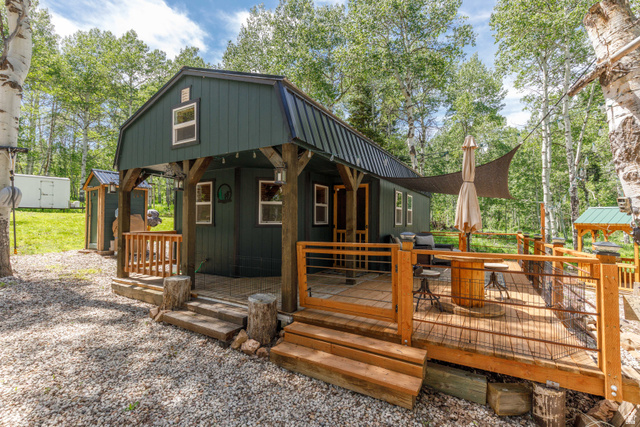 12 Scare Canyon Paradise, UT 84328 - Photo 1 of 1 Dark green barn-style dwelling featuring a covered porch with exposed timber framing and a spacious wood deck