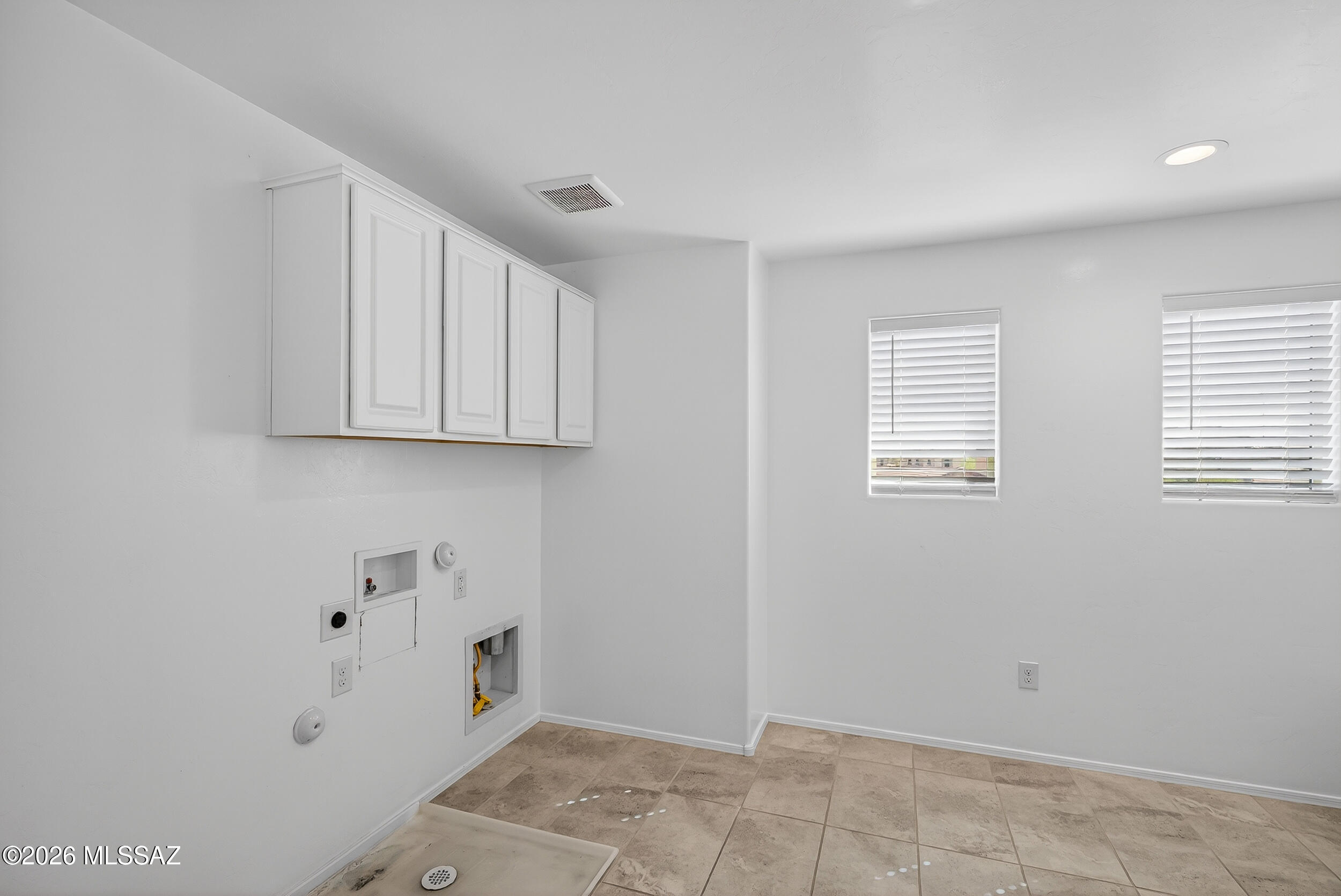 7556 South Circulo Rio Blanco Tucson, AZ 85756 - Photo 28 of 50 Massive, bright laundry room with abundant natural light from multiple windows, white upper cabinetry, built-in utility niches, durable tile flooring, and generous space for appliances, folding, and storage.