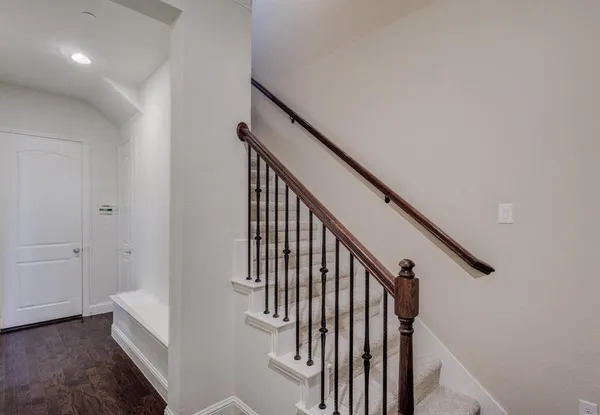 a view of staircase with railing and white walls