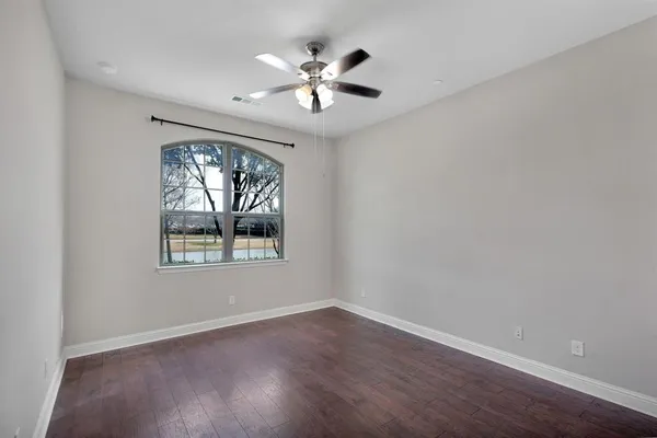 an empty room with wooden floor chandelier fan and windows