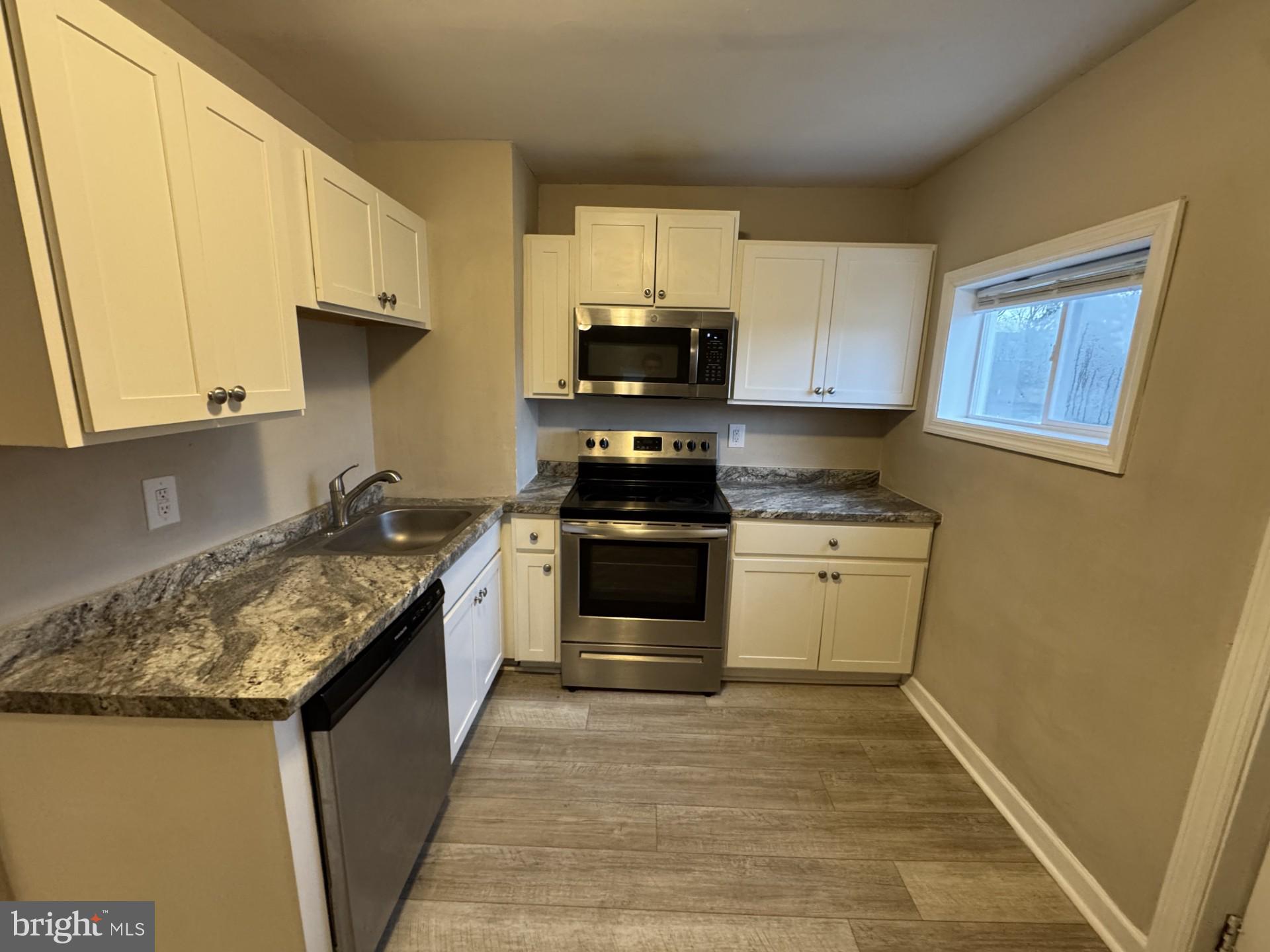 3920 Main Street, Unit A Trappe, MD 21673 - Photo 4 of 16 a kitchen with granite countertop a stove and cabinets