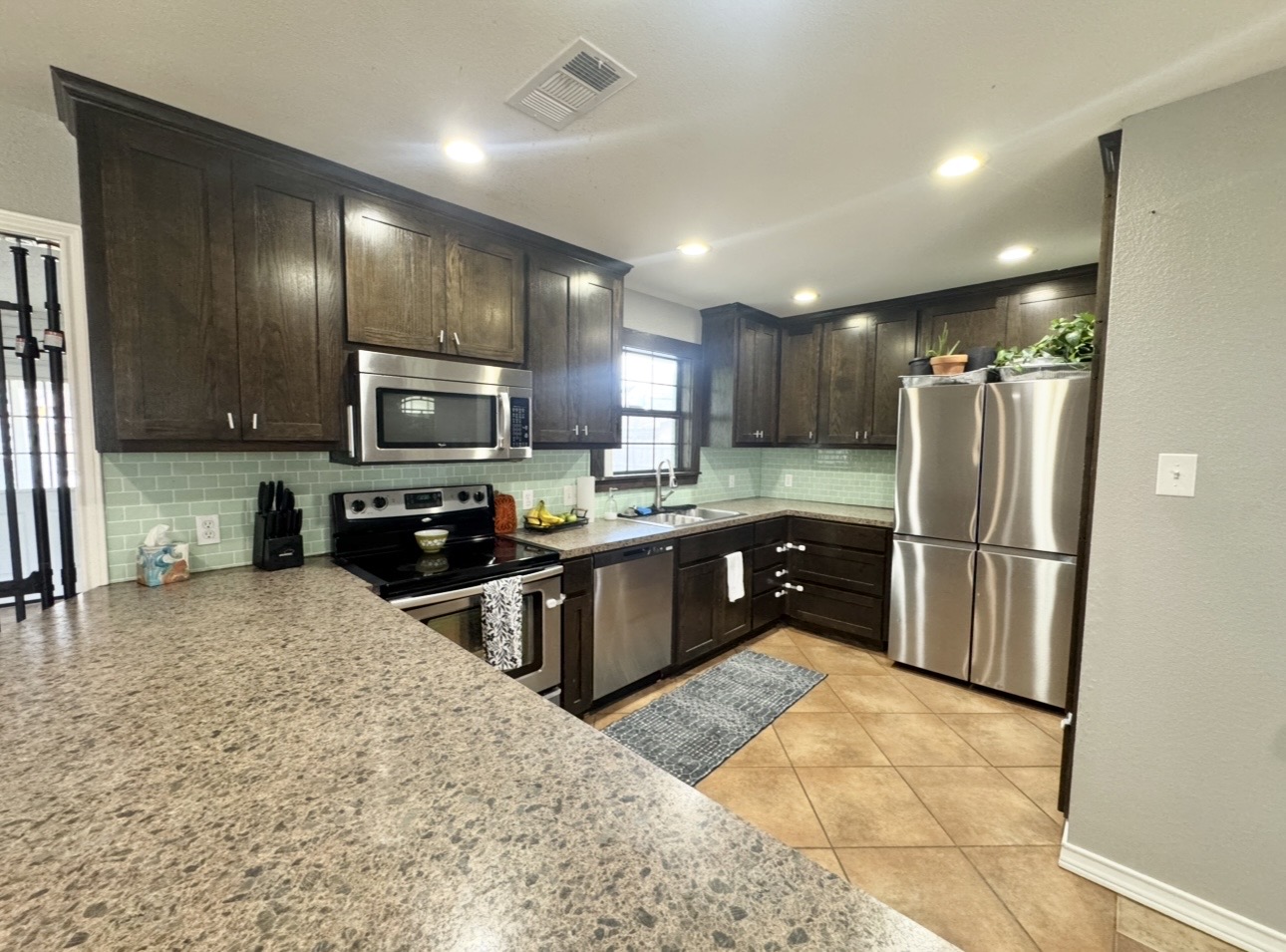 612 Cardinal Street Elgin, TX 78621 - Photo 11 of 28 Kitchen with stainless steel appliances, dark wood finish cabinets, tasteful backsplash, light tile patterned floors, and recessed lighting
