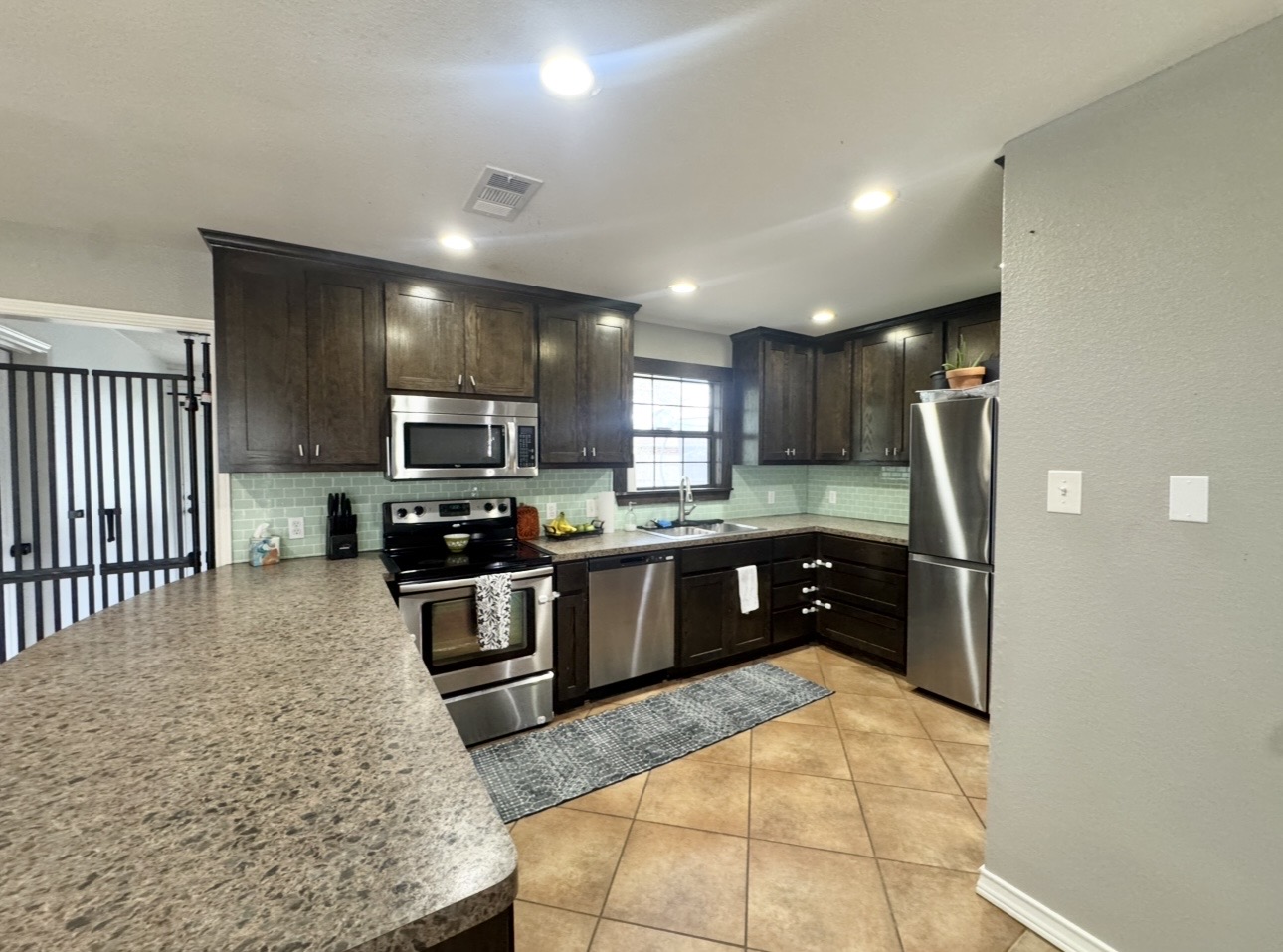 612 Cardinal Street Elgin, TX 78621 - Photo 10 of 28 Kitchen featuring stainless steel appliances, light tile patterned floors, a peninsula, dark wood finish cabinets, and recessed lighting