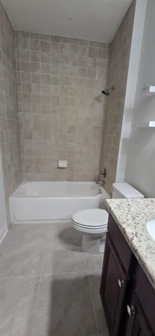 a bathroom with a granite countertop bathtub shower sink vanity and toilet
