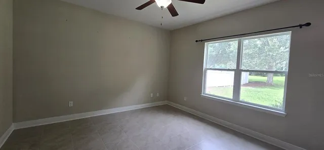 an empty room with a window and a ceiling fan