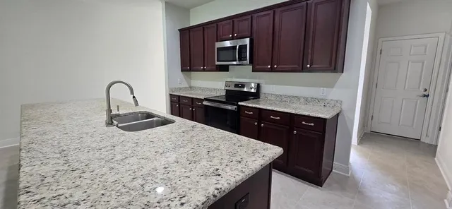 a kitchen with granite countertop a sink a stove and cabinets