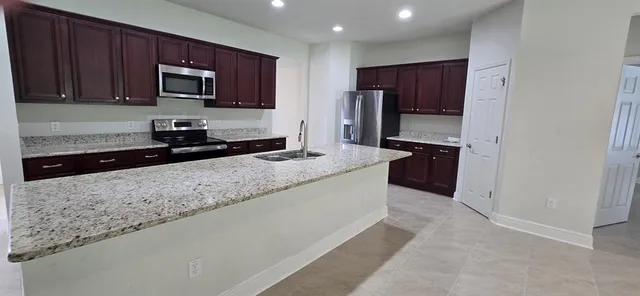a kitchen with stainless steel appliances granite countertop a stove a sink and a microwave