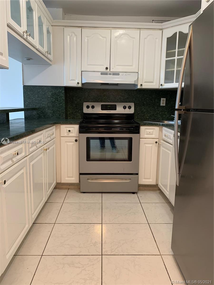 1325 West 68th Street, Unit 514 Hialeah, FL 33014 - Photo 7 of 20 a kitchen with granite countertop white cabinets and appliances