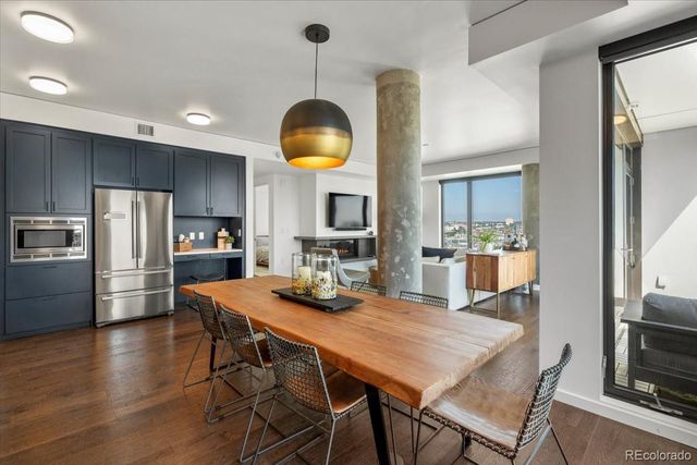 a kitchen with stainless steel appliances a dining table chairs and wooden floor