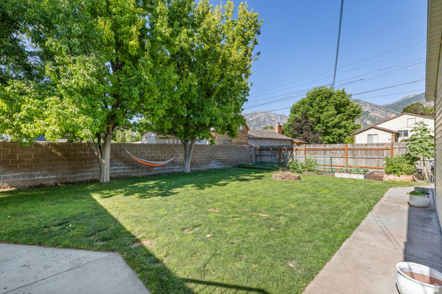 594 850 West Provo, UT 84601 - Photo 17 of 33 Spacious backyard featuring a large grass area, mature trees, a concrete patio, and a cinder block privacy wall
