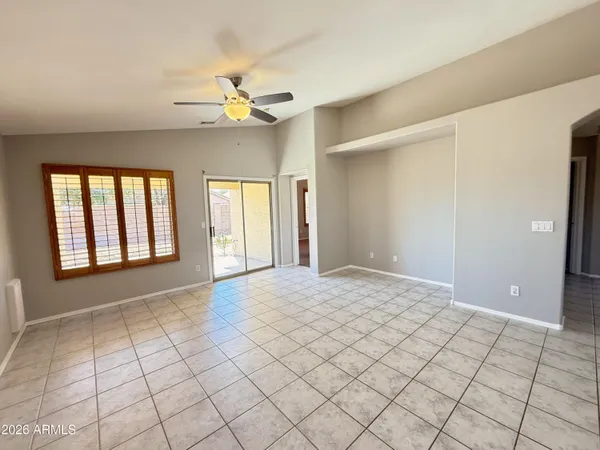 a view of an empty room with window and chandelier fan