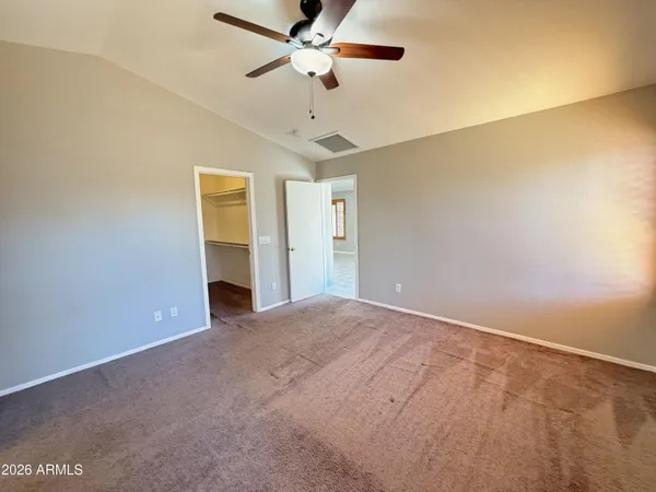 a view of an empty room with chandelier fan and a window