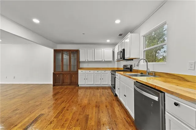 a large kitchen with stainless steel appliances granite countertop a lot of counter space and wooden floors